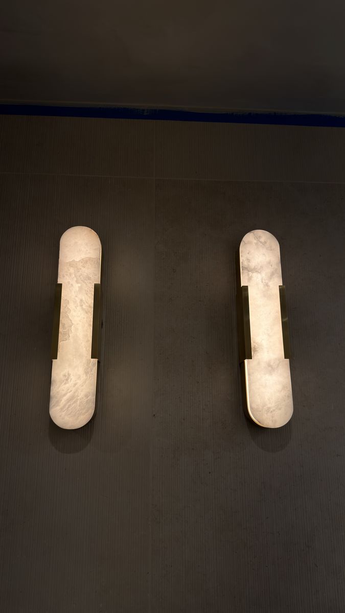 Alabaster and brass wall sconces mounted on an interior wall