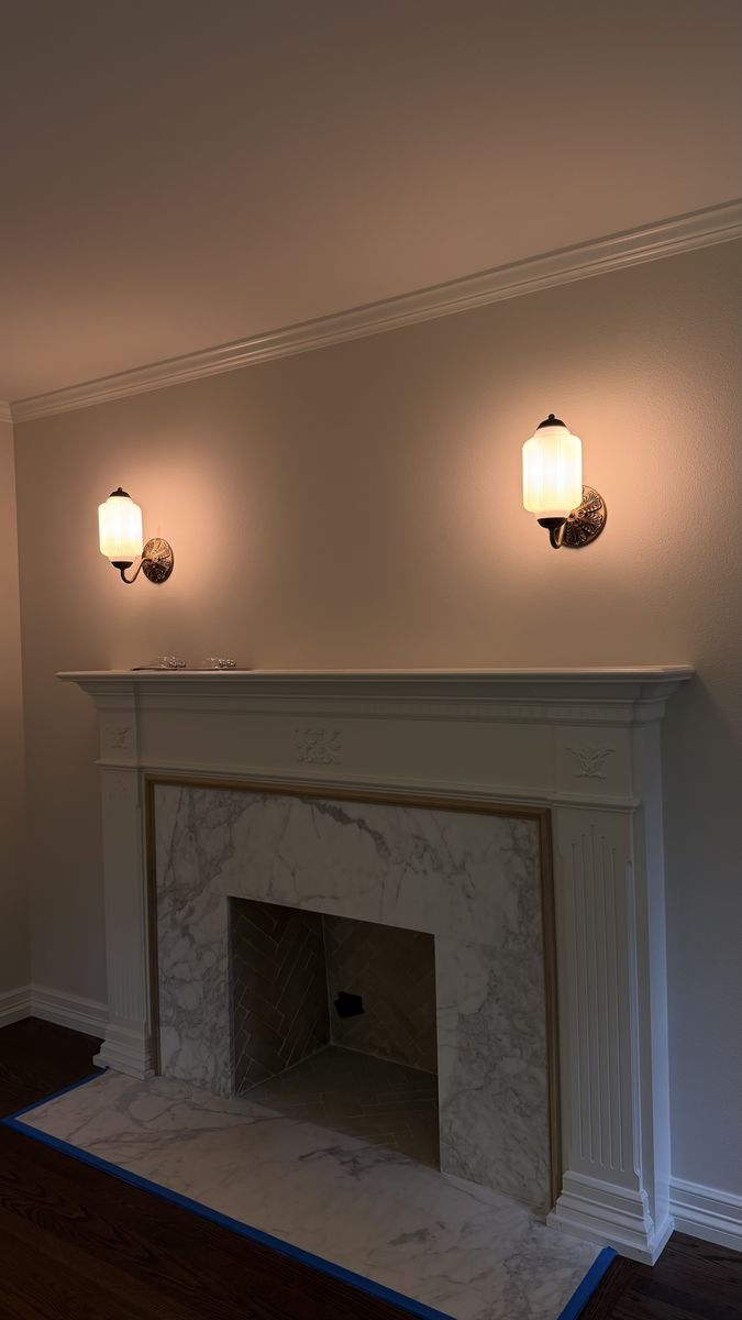 Pair of glass wall sconces mounted above a fireplace mantel