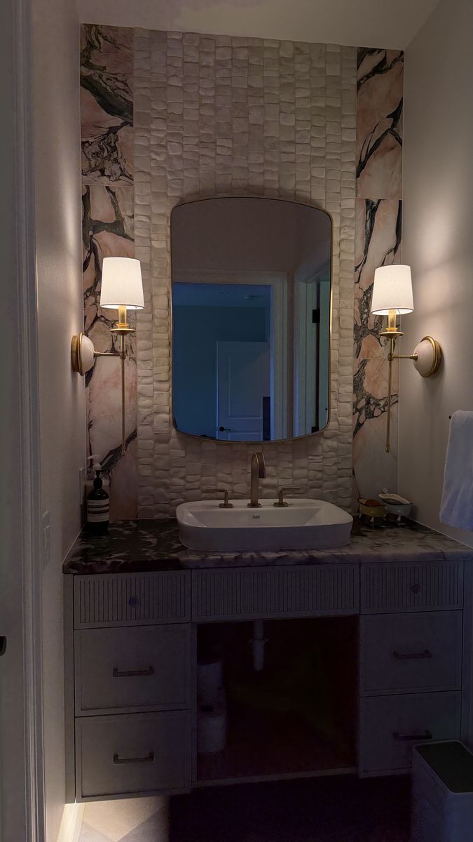 Brass shaded sconces on either side of a bathroom vanity mirror
